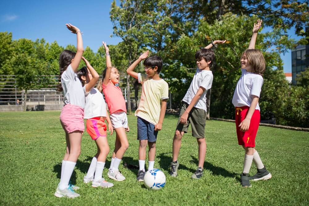 6 jeunes enfants sur un terrain de foot qui se check les mains