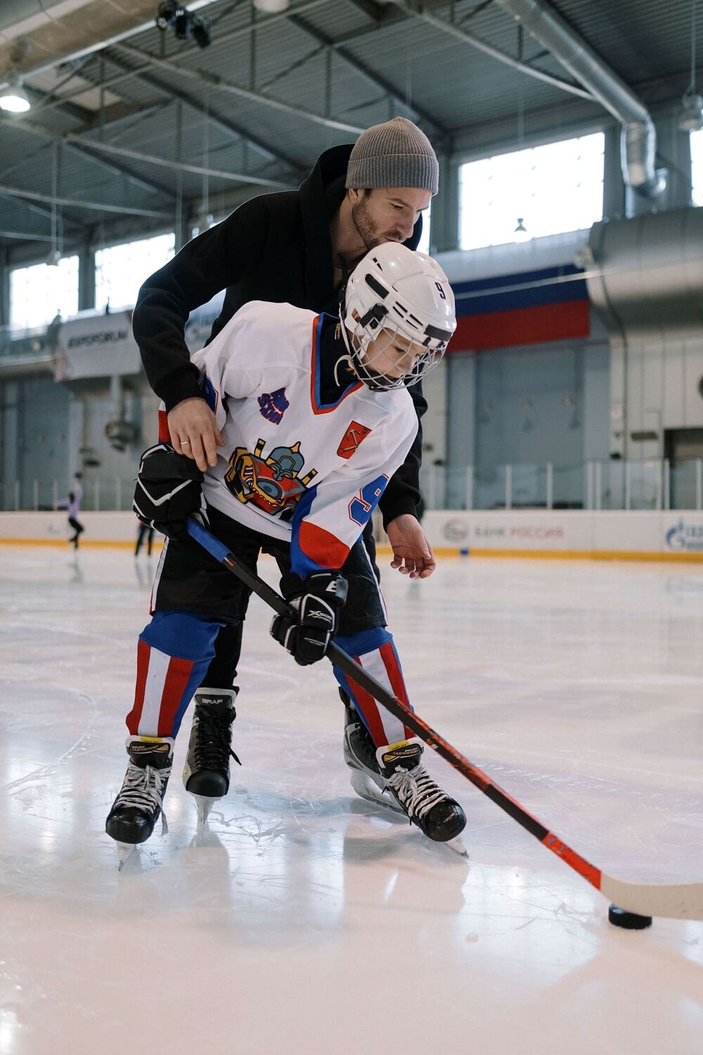 un adulte entraine un enfant au hockey sur glace