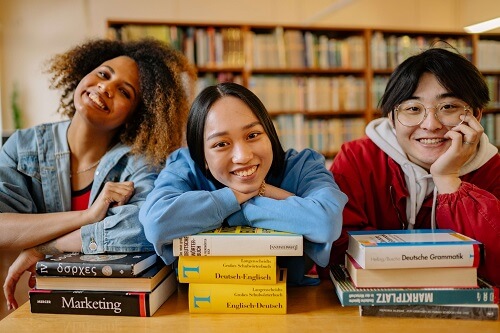 3 lycéens joyeux dans une biblothèque
